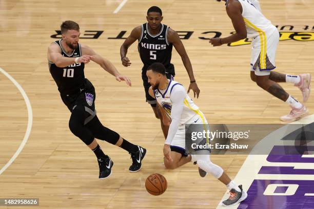 Stephen Curry of the Golden State Warriors is guarded by Domantas Sabonis and De'Aaron Fox of the Sacramento Kings in the first half during Game Two...