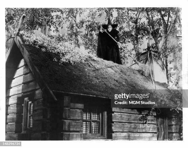 Margaret Hamilton as the Wicked Witch of the West on top of a roof with her broom in a scene from the film 'The Wizard Of Oz', 1939.