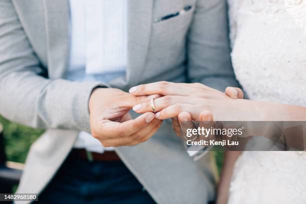 groom putting ring on bride's finger. rings exchange. happy couple celebrating wedding outdoors. - hochzeit stock-fotos und bilder