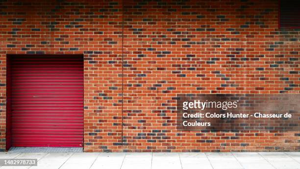 brick wall with closed rolling garage door and cement slabs floor in london, england, united kingdom - industrial doors stock pictures, royalty-free photos & images