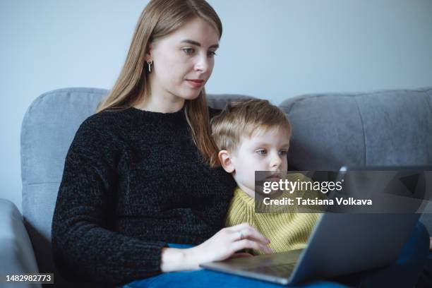 a woman, a freelancer, a mom and her child, a little boy, 5 years old, using a laptop while sitting on the couch. - 30 34 years bildbanksfoton och bilder