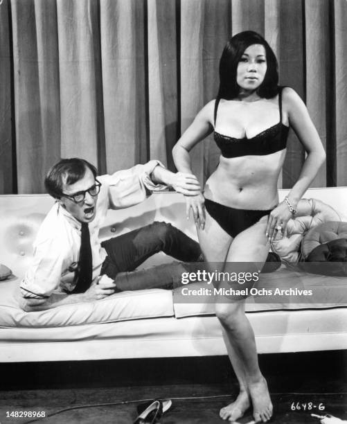 Woody Allen reacting as Akiko Wakabayashi flaunts herself in a scene from the film 'What's Up, Tiger Lily?', 1966.