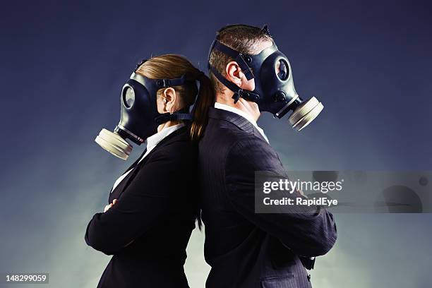 formally-dressed couple in gas masks stand backs to each other - bad breath stock pictures, royalty-free photos & images