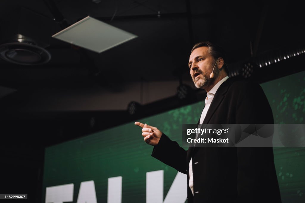 Low angle view of mature tech entrepreneur gesturing while giving speech at tech event