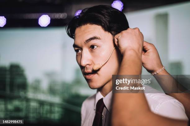 hand of man adjusting microphone of male tech entrepreneur at seminar - no fixed address stock pictures, royalty-free photos & images