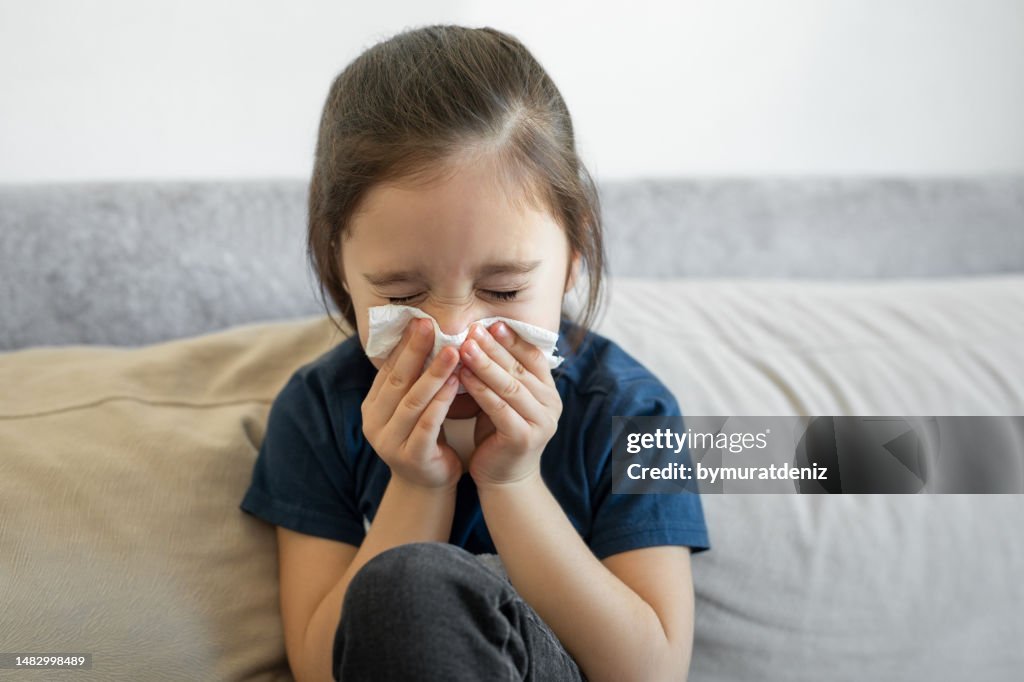 Girl cleaning her nose at sofa