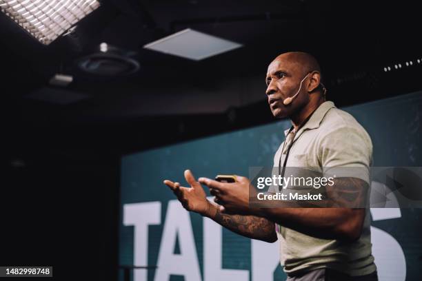 serious male public speaker gesturing while giving speech at tech event - orador público fotografías e imágenes de stock