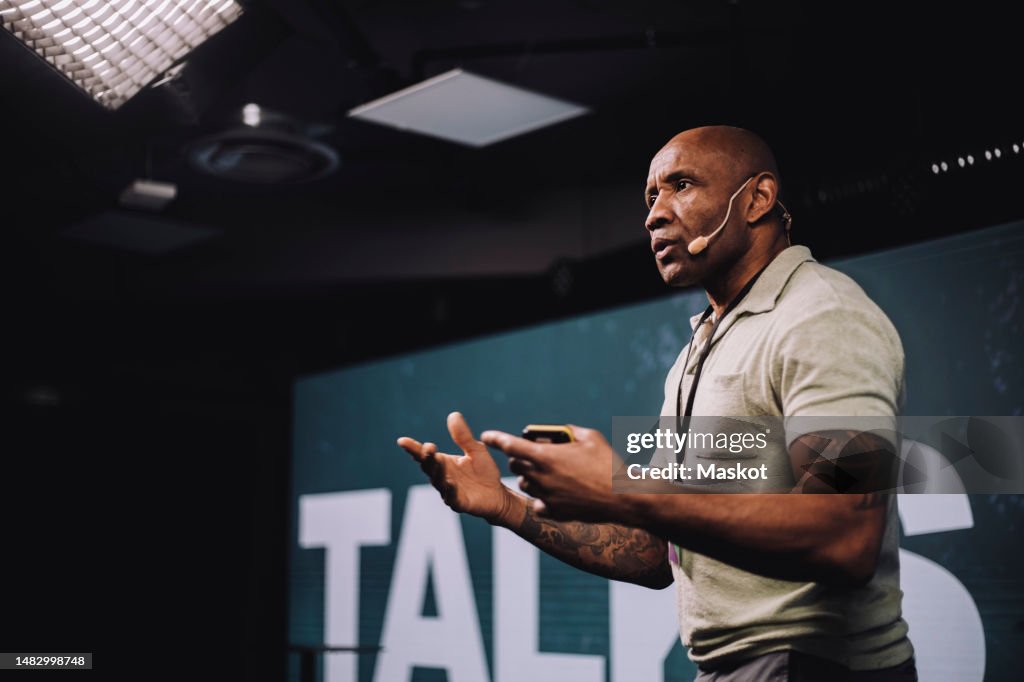 Serious male public speaker gesturing while giving speech at tech event