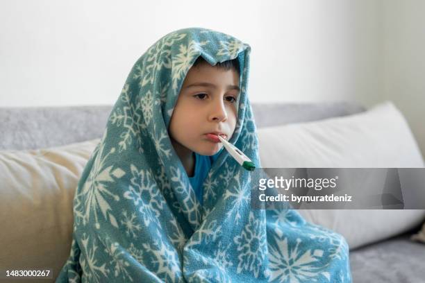 menino doente com termômetro no sofá - flu virus - fotografias e filmes do acervo