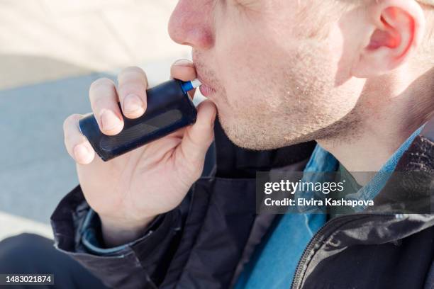 a 39 year old man smokes electronic cigarettes, close up. smoking sticks with a tobacco heating device - vaping danger stock pictures, royalty-free photos & images