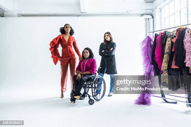 portrait of female fashion designer in wheelchair with female models - hohlkehle stock-fotos und bilder