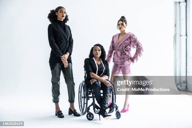 portrait of female fashion designer in wheelchair with female models - cyclorama achtergrond stockfoto's en -beelden