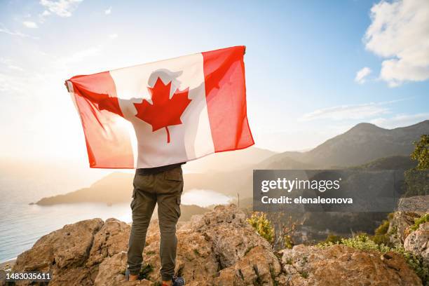 man with canadian flag on the background of the sea and mountains - canadians celebrate national day of independence stock pictures, royalty-free photos & images