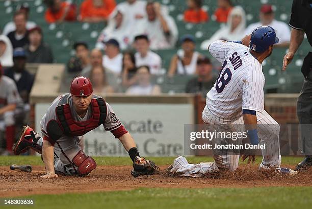 Geovany Soto of the Chicago Cubs scores a run on a squeeze play as Miguel Montero of the Arizona Diamondbacks misses the tag at Wrigley Field on July...
