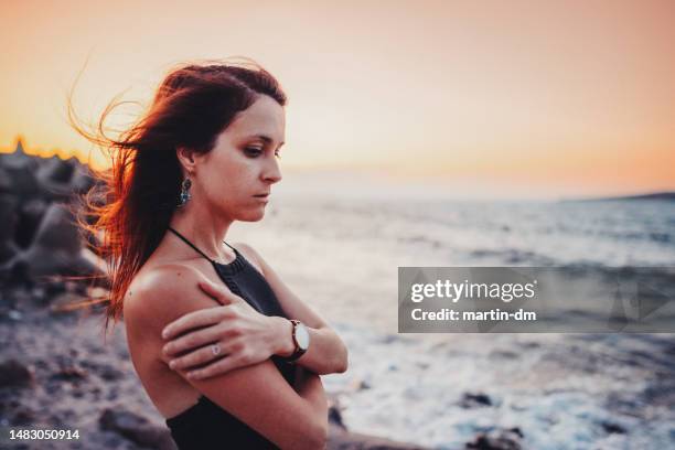 frau am meer mit blick auf den sonnenuntergang - gänsehaut frau stock-fotos und bilder