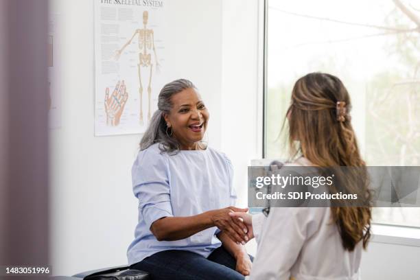 female patient shakes hands with the female healthcare professional - empathetic listening stock pictures, royalty-free photos & images