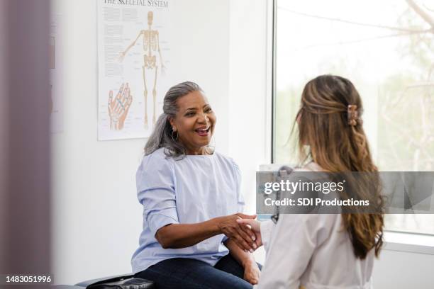 female patient shakes hands with the female healthcare professional - cuidados de saúde primários imagens e fotografias de stock