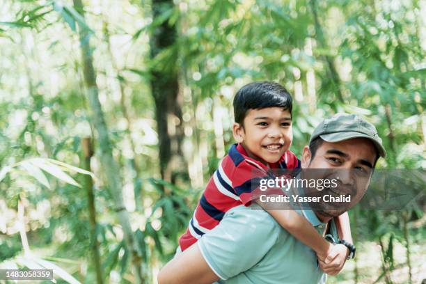 father carrying his son on the back - malay archipelago stock pictures, royalty-free photos & images