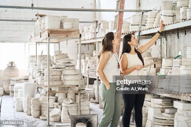 frau mit manager, die sich keramische produkte ansieht, die formen auf einem gestell in der fabrik herstellen - shaping future stock-fotos und bilder