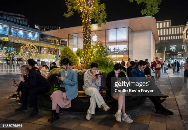 People sit on a bench outside an Apple Store in a busy retail shopping area on April 18, 2023 in Beijing, China. China's National Bureau of...