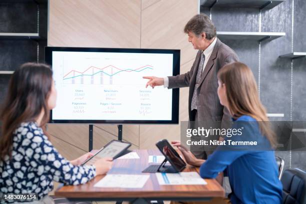 increase team communication at project status meetings help the project manager in building trust in the team. male project manager in a meeting to follow up on the project status on an interactive screen in a business office. - finanzanalyst stock-fotos und bilder
