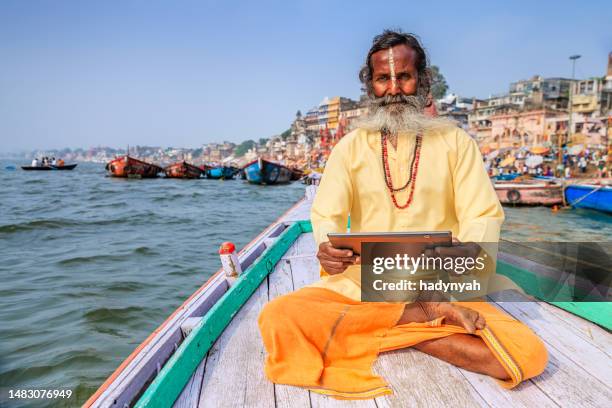 sadhu mit digitalem tablet im boot auf dem holy ganges river, varanasi - brahmin stock-fotos und bilder