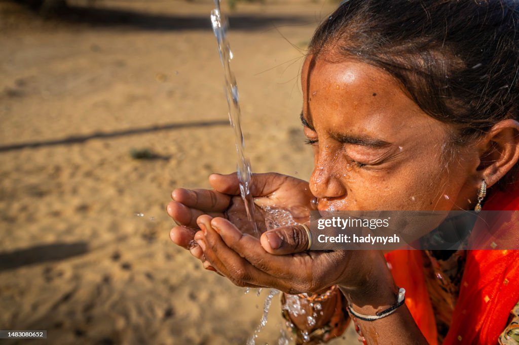 Jeune fille indienne buvant de l’eau douce, village du désert, Rajasthan, Inde