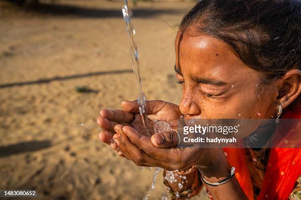 indian young girl drinking fresh water, desert village, rajasthan, india - drinkwaterfontein stockfoto's en -beelden