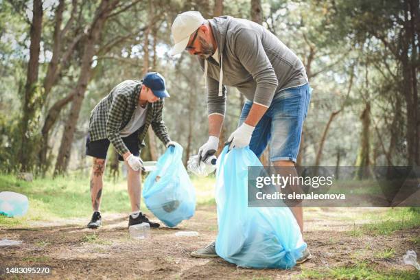 father and son clean up trash in the forest - garbage man stockfoto's en -beelden