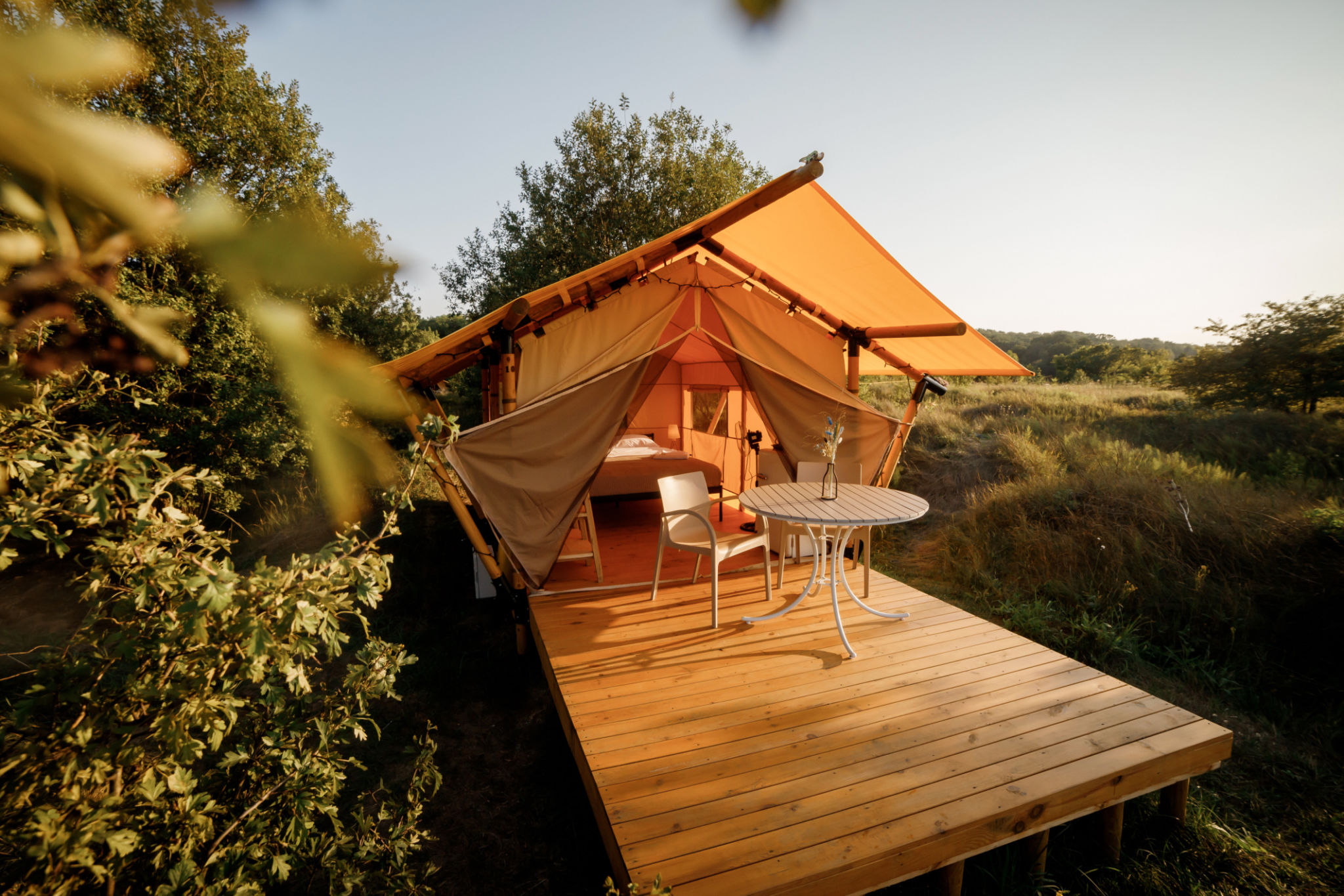 Cozy open glamping tent with light inside during sunset. Luxury camping tent for outdoor summer holiday and vacation. Lifestyle concept Cozy open glamping tent with light inside during sunset. Luxury camping tent for outdoor summer holiday and vacation. Lifestyle concept