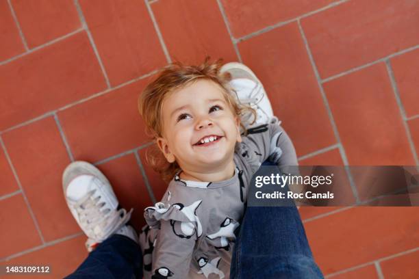 a smiling 2 year old girl looking up, playing with her father - 2 year old blonde girl father ストックフォトと画像