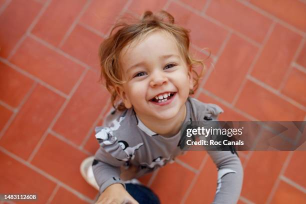 a smiling 2 year old girl looking up, playing with her father - 2 year old blonde girl father ストックフォトと画像
