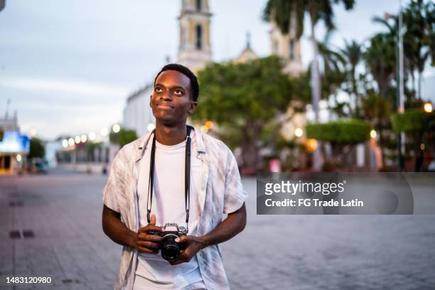 young man walking and looking around exploring the city - wanderer pause stockfoto's en -beelden