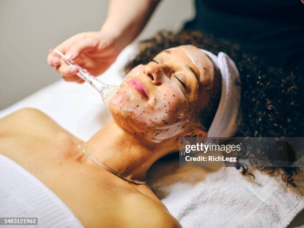 woman in a day spa receiving a facial treatment - exfoliant stock pictures, royalty-free photos & images
