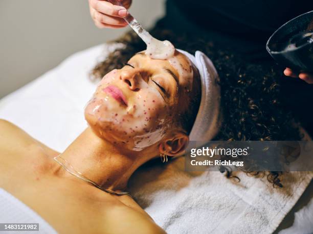 woman in a day spa receiving a facial treatment - beauty mask stock pictures, royalty-free photos & images