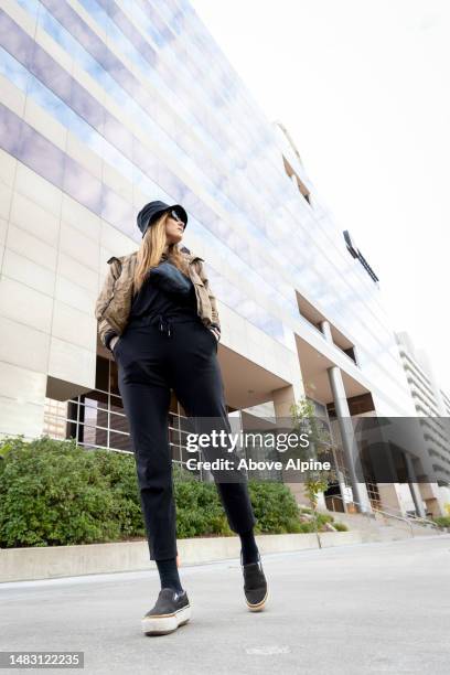 schöne kaukasische erwachsene frau, die allein in den straßen der innenstadt von denver colorado street style mode steht - athleisure stock-fotos und bilder