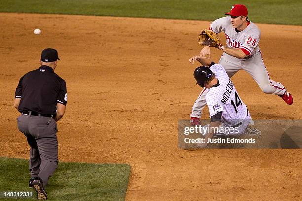 Josh Rutledge of the Colorado Rockies steals second base ahead of the tag by Chase Utley of the Philadelphia Phillies under the watchful eye of...