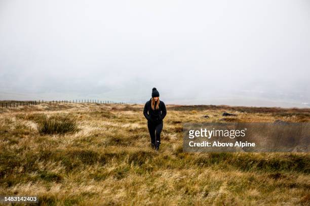woman walking in open field depressed fog and overcast weather - pursuit sports competition format stock pictures, royalty-free photos & images
