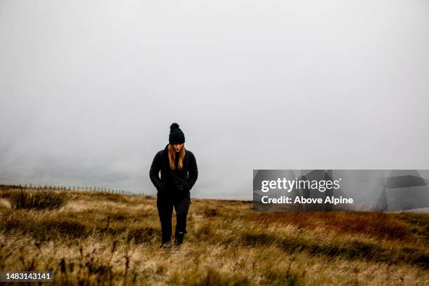 woman walking in lonely open depressed field in rainy england fog copy space - pursuit sports competition format stock pictures, royalty-free photos & images