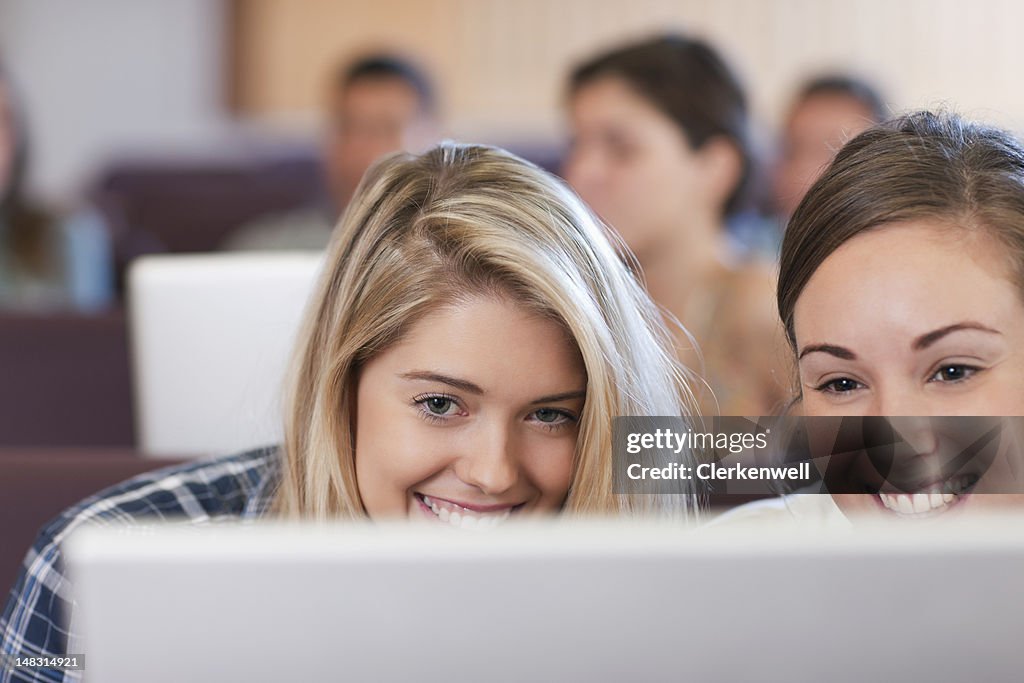 Smiling university students using laptop