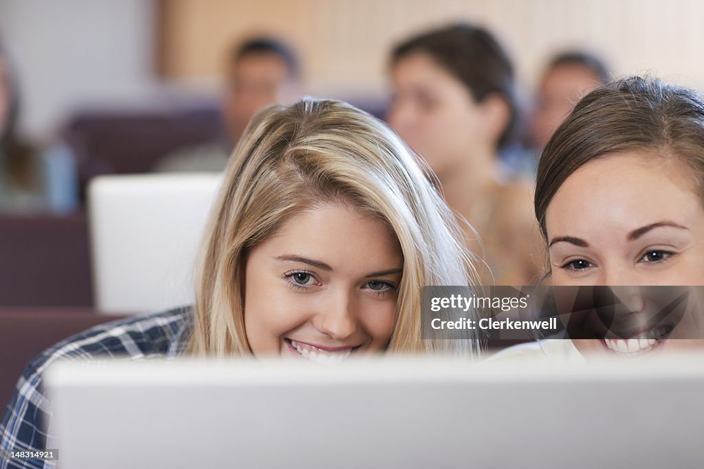 Sorridente estudantes universitários usando computador portátil