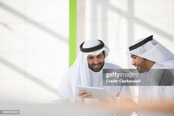 businessmen in kaffiyehs using digital tablet - dish dash stock pictures, royalty-free photos & images