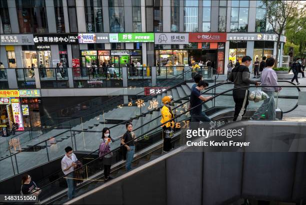 People ride on an escalator in a busy retail shopping area on April 18, 2023 in Beijing, China. Chinas Chinas National Bureau of Statistics reported...