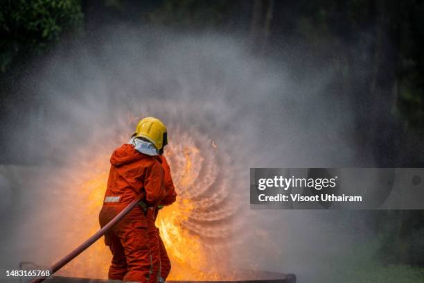 firefighter battling flame,fireman using extinguisher and water from hose for fire fighting. - brandslang stockfoto's en -beelden