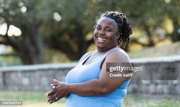 afroamerikanische frau in übergröße im park, lächelnd - capped tooth stock-fotos und bilder