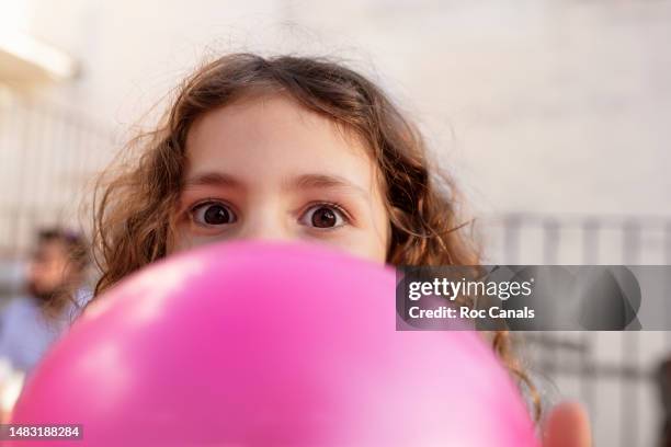 6 year old girl blowing up a balloon - kids party balloons stock-fotos und bilder