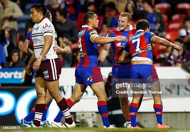 Tyrone Roberts of the Knights celebrates with team mates Timana Tahu and Alex McKinnon after scoring against the Sea Eagles during the round 19 NRL...