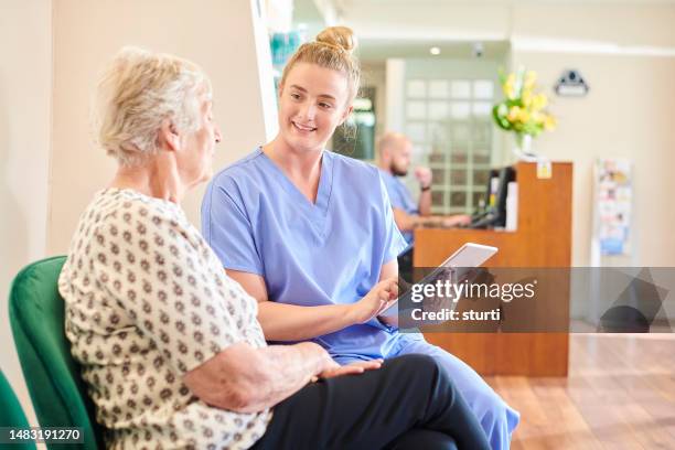 zahnarzthelferin unterhält sich mit älterem patienten - zahnarzthelfer stock-fotos und bilder