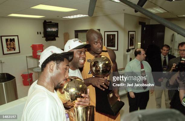 Shaquille O''Neal of the Los Angeles Lakers poses with Magic Johnson and Kobe Bryant in the locker room with the trophies after winning the NBA...