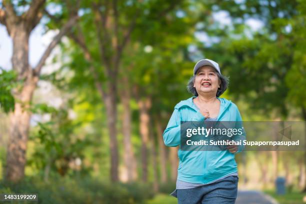 portrait of asian senior woman running and exercising in the park.elderly woman enjoying a day in the park on summer. healthcare lifestyle and wellness. - day of yoga in bangkok stock-fotos und bilder